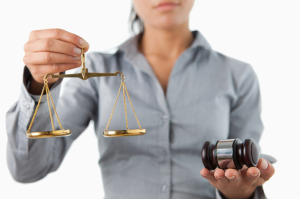 Gavel and scale being held by female lawyer against a white back